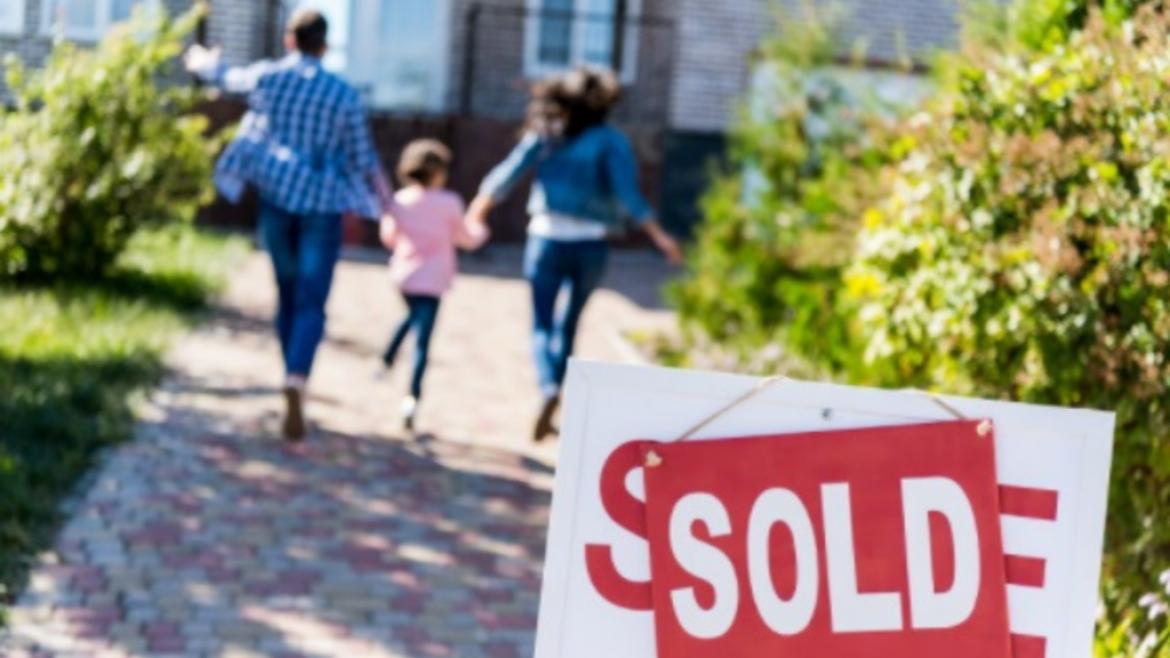family walking to house with Sold sign in yard
