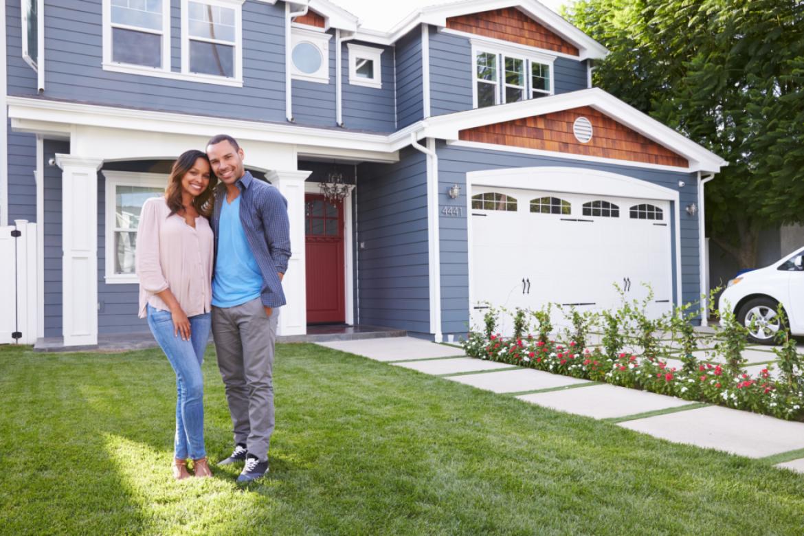 young couple standing in front of new home